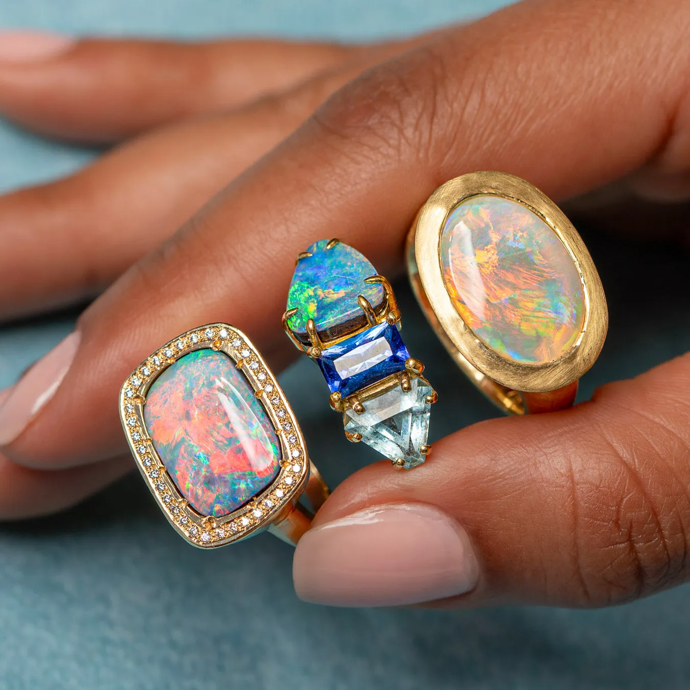Three statement opal and gemstone rings worn on a hand