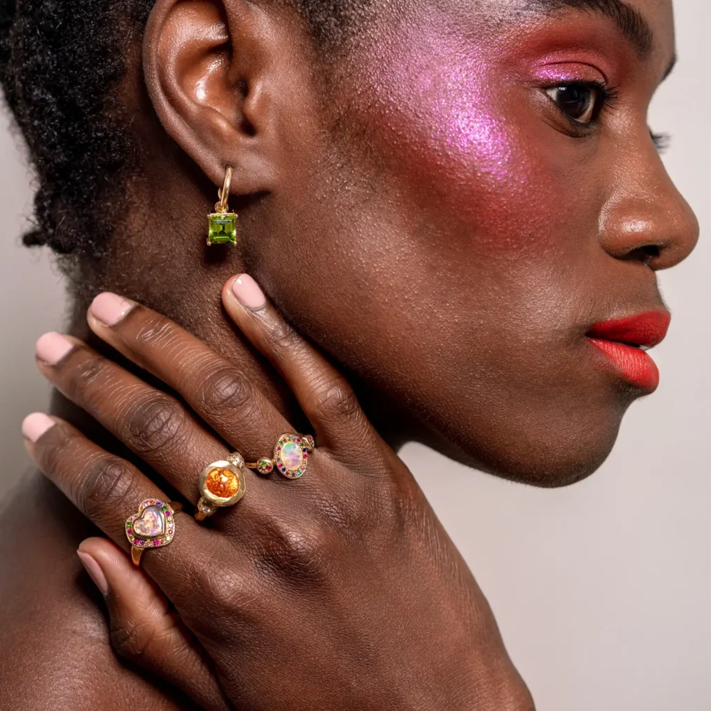 Model wearing luxury gold tourmaline earrings and multiple rings editorial shoot