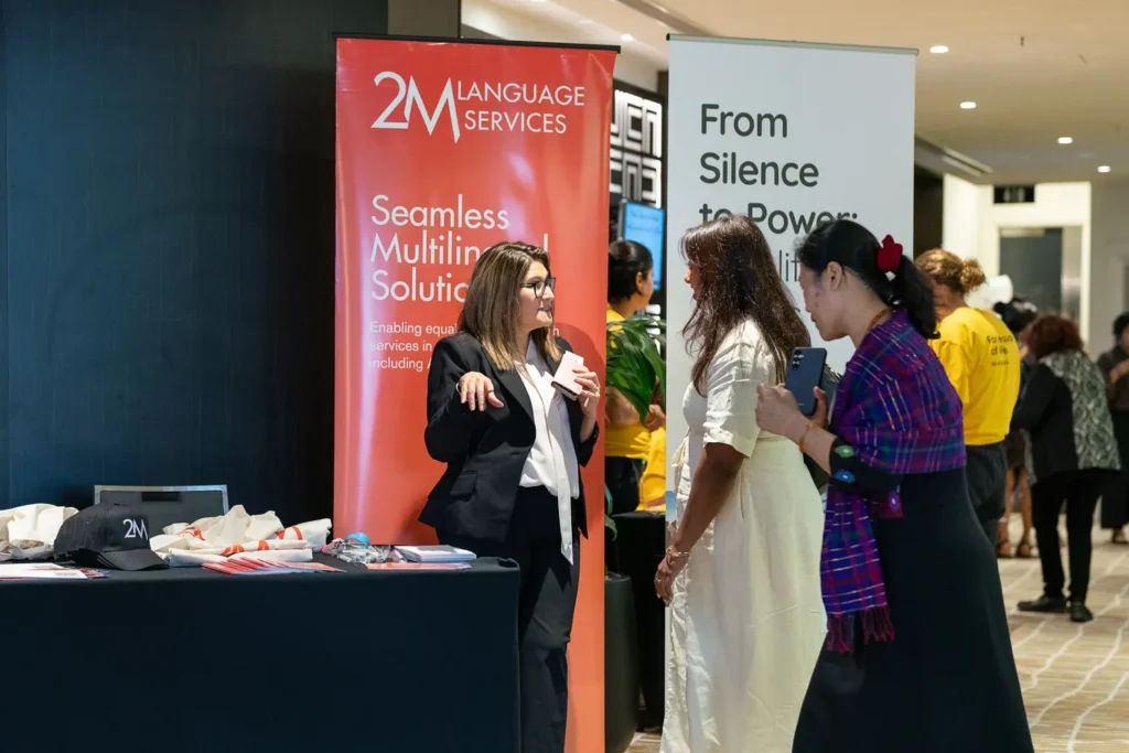Guests arriving near the 2M Language Services sponsor display at the conference in Parramatta