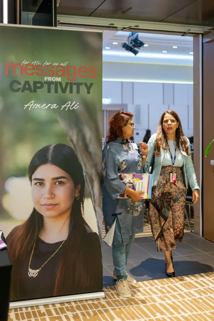 Messages from Captivity banner beside guests arriving at the conference venue