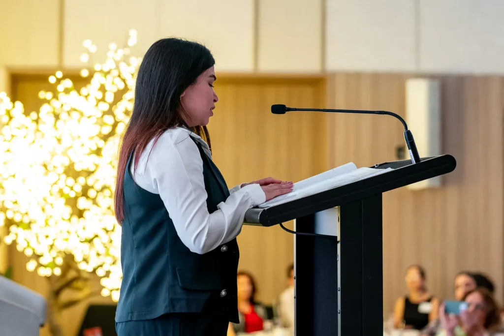 Amera Ali speaking at the podium during the book launch event at PARKROYAL Parramatta