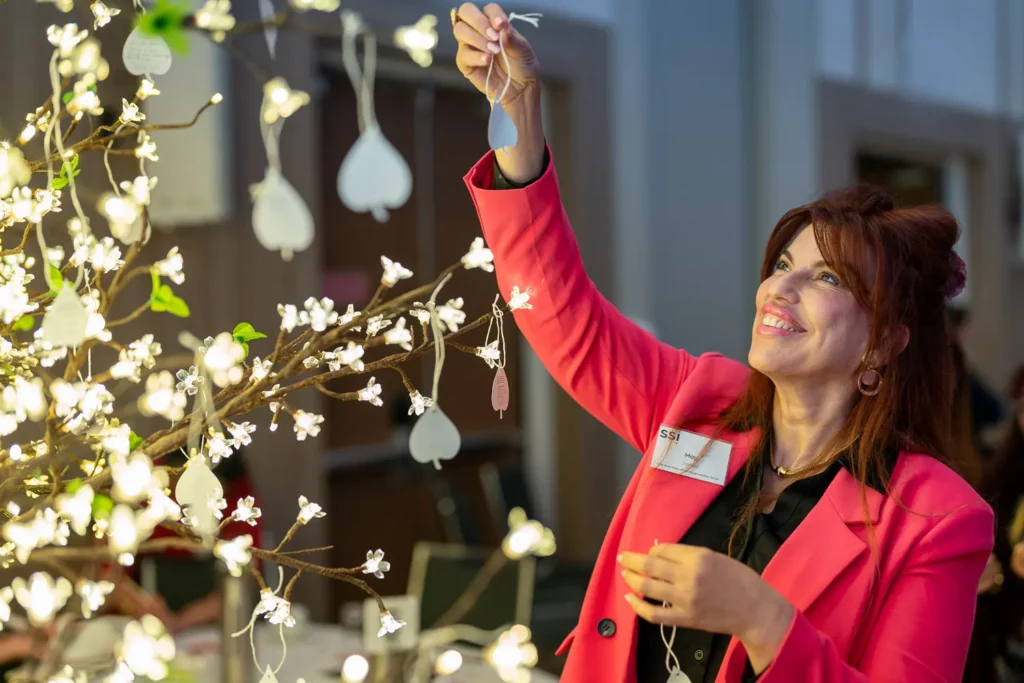 Guest hanging a commitment leaf on the illuminated tree at the conference