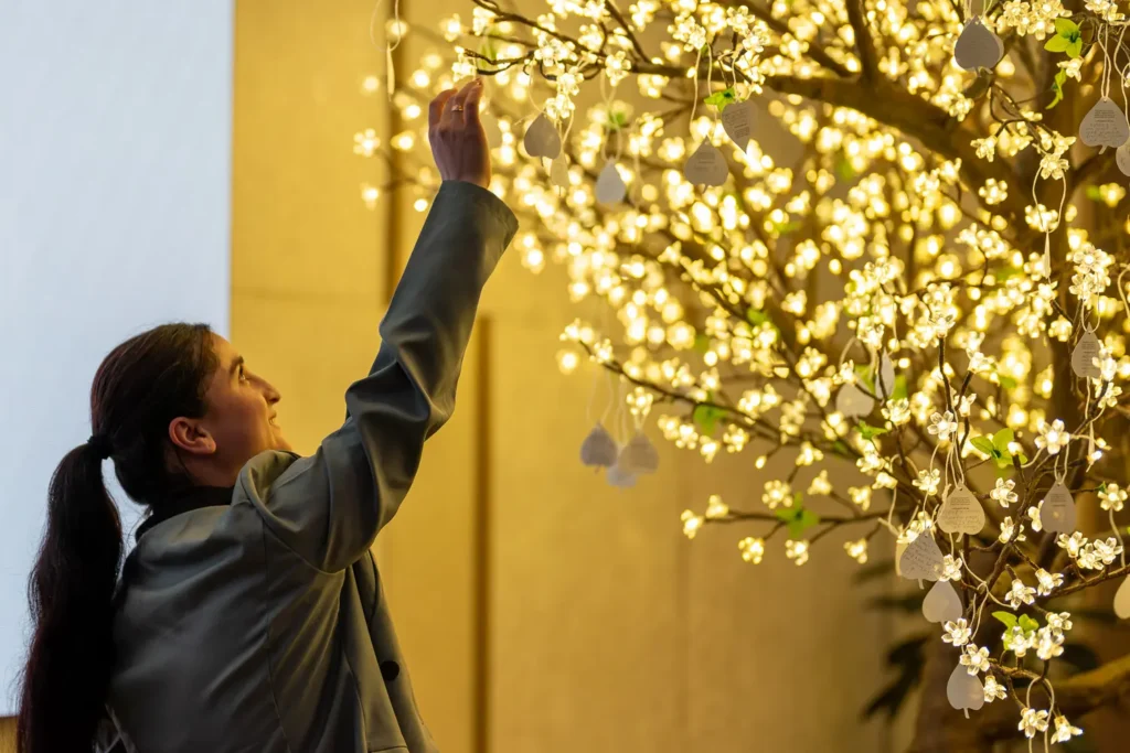 Guest placing a commitment leaf on the illuminated tree during the event