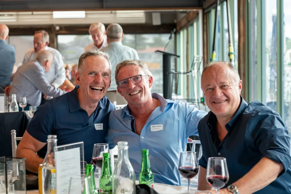 Three guests smiling together at a table during the Michael Morgan OAM lunch