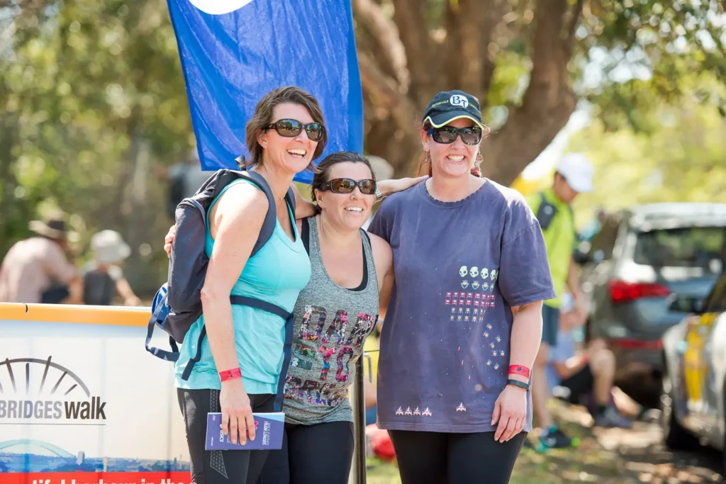 Three participants smiling during the Bridges Walk charity event in Sydney