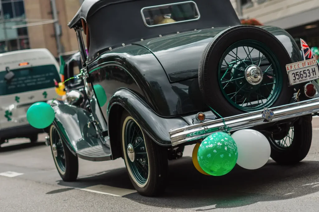 Classic vintage car decorated with green balloons during Irish festival parade