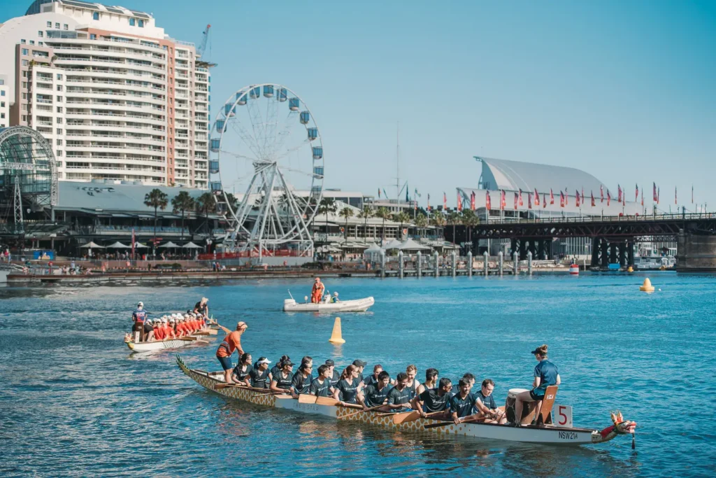 Dragon boat crews paddling through Darling Harbour during corporate race event