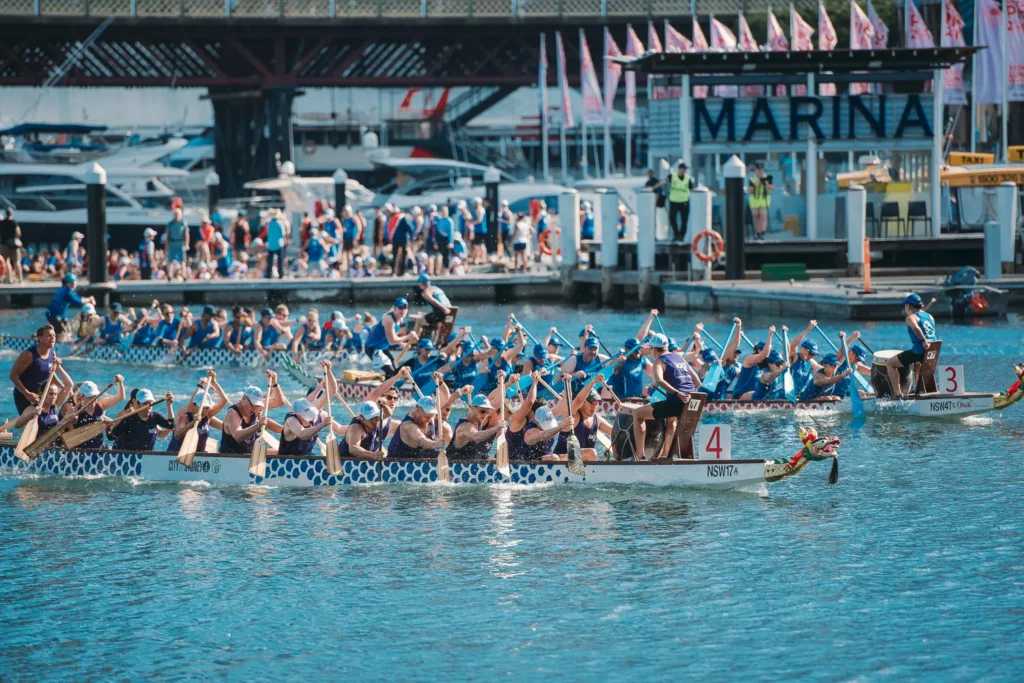 Multiple dragon boat teams competing near marina docks at Darling Harbour