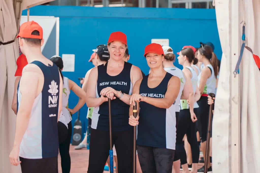 Two NSW Health dragon boat participants posing with paddles before the race event in Sydney