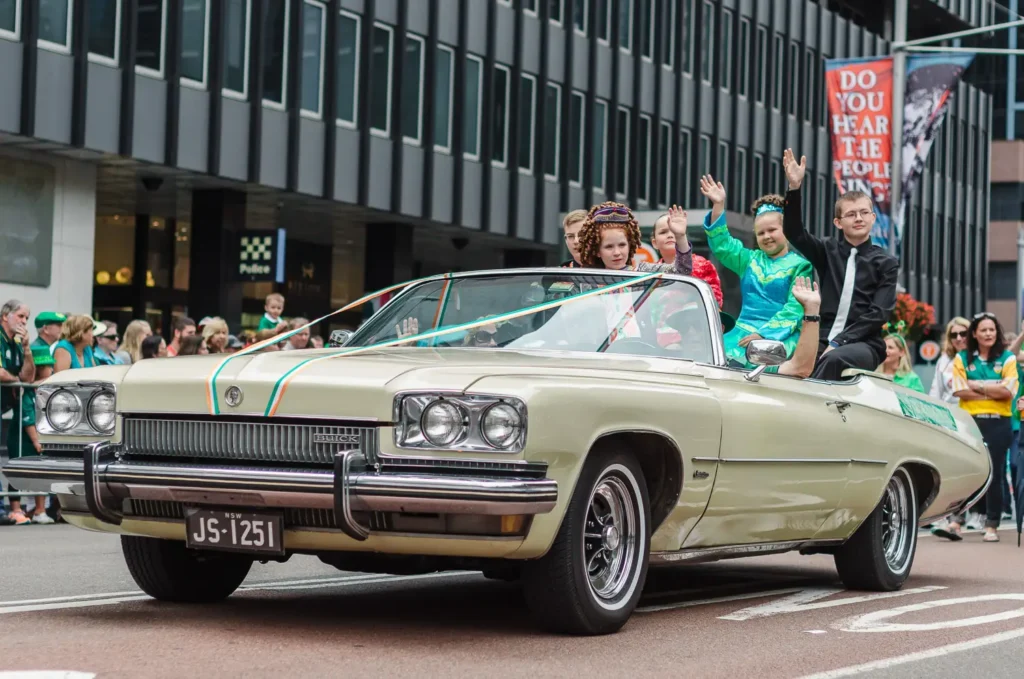 Vintage Buick convertible carrying parade participants through Sydney CBD