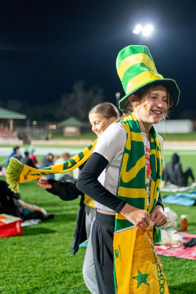 Young Matildas supporter smiling while wearing Australia scarf and hat at North Sydney Oval live site