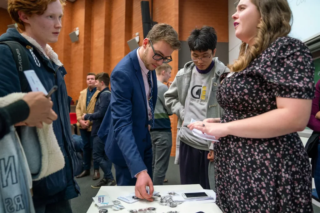 Conference attendees gathering around a table after a presentation