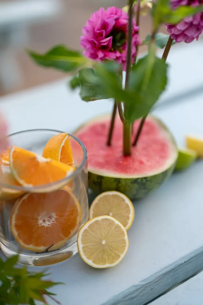 Colourful citrus fruit, watermelon and pink flowers used as event styling
