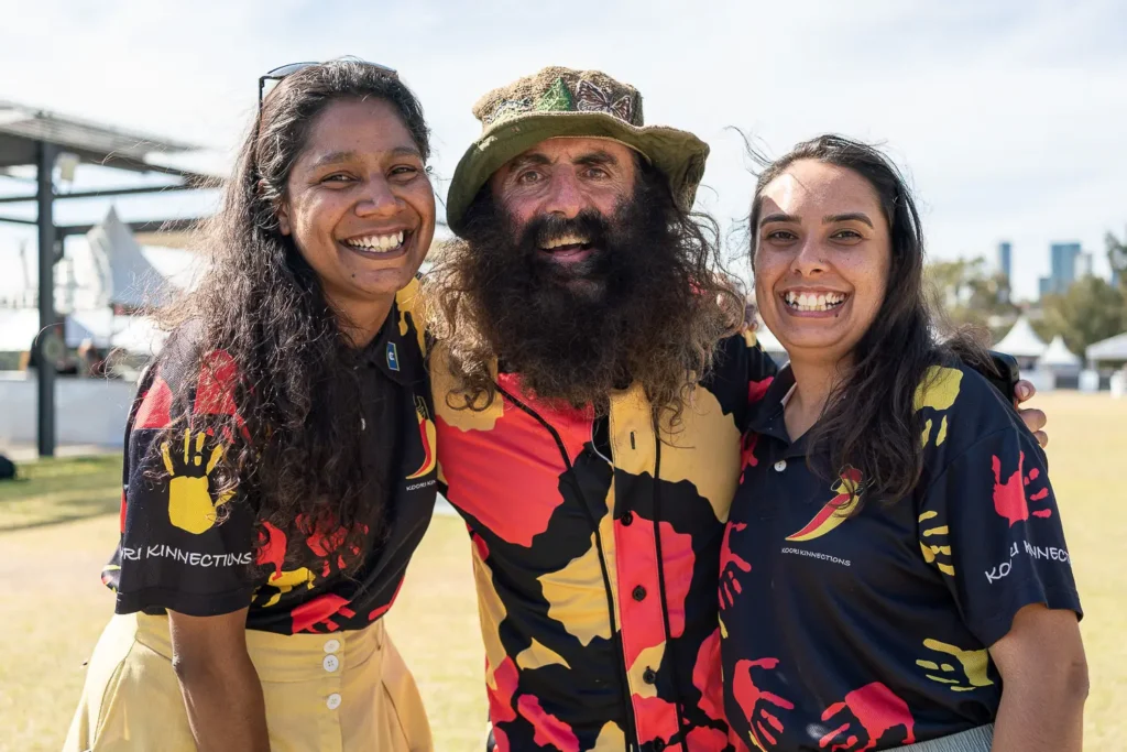 Three smiling community festival participants posing together outdoors