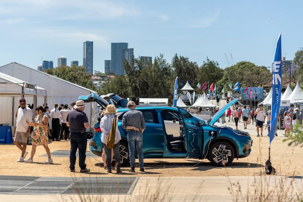 Electric vehicle on display with doors open at an outdoor sustainability festival