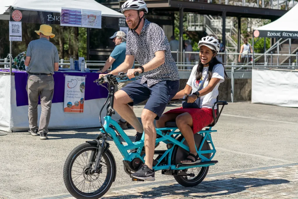 Two people enjoying an electric cargo bike demonstration at a sustainability festival