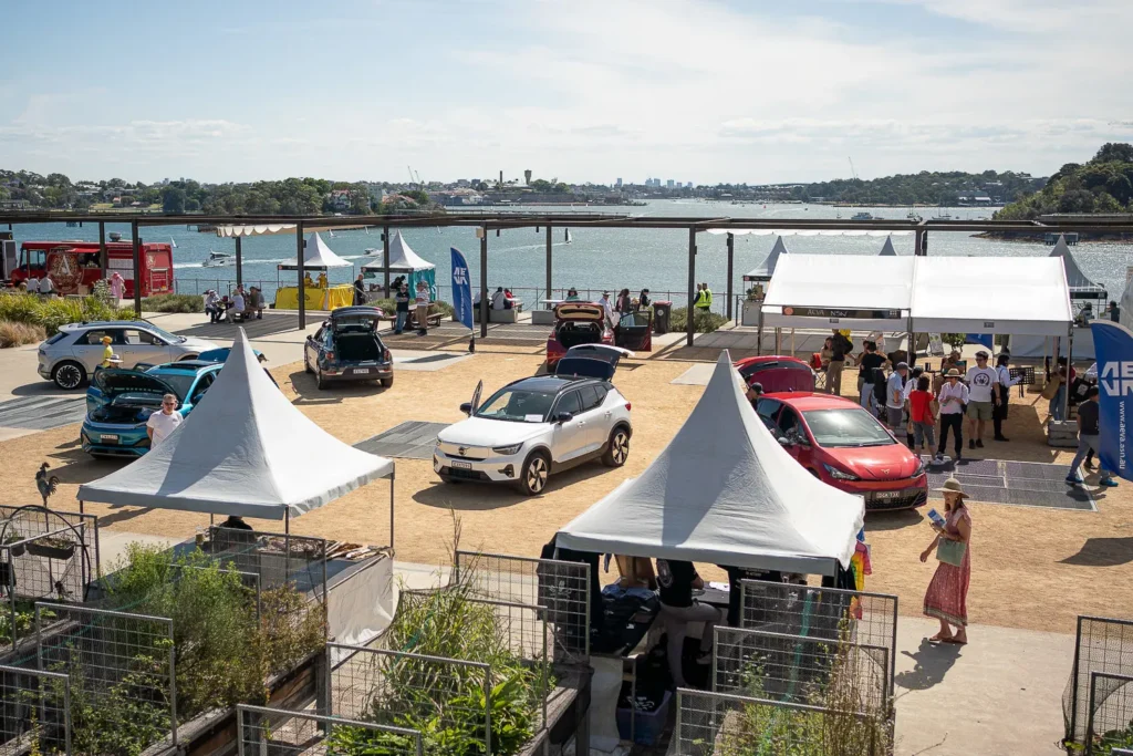 Electric vehicles and festival stalls at a waterfront sustainability event in Sydney