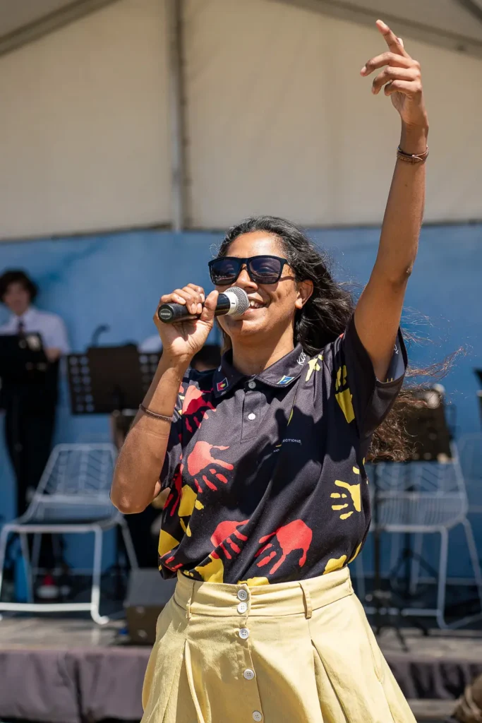 Festival host speaking into a microphone during a live outdoor event