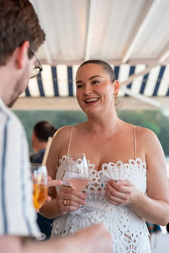 Smiling guest holding a glass of rosé while networking at the Shift soirée