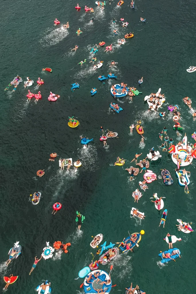 Drone view of participants racing across the water on colourful inflatables at Shelly Beach