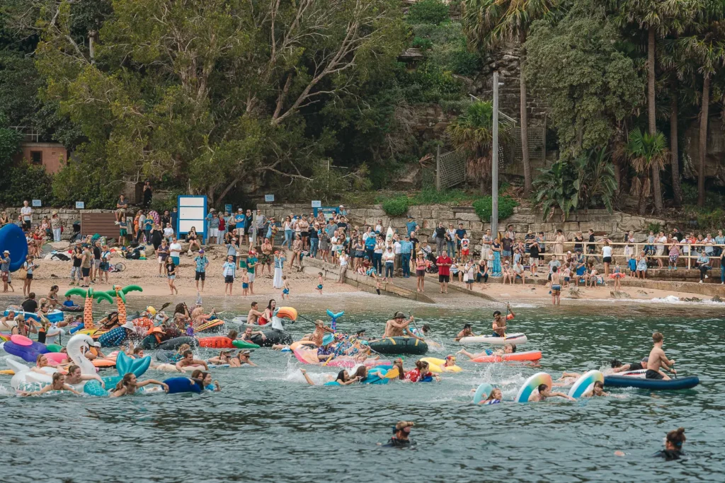 Large crowd watching colourful inflatable racers from the beach at Manly