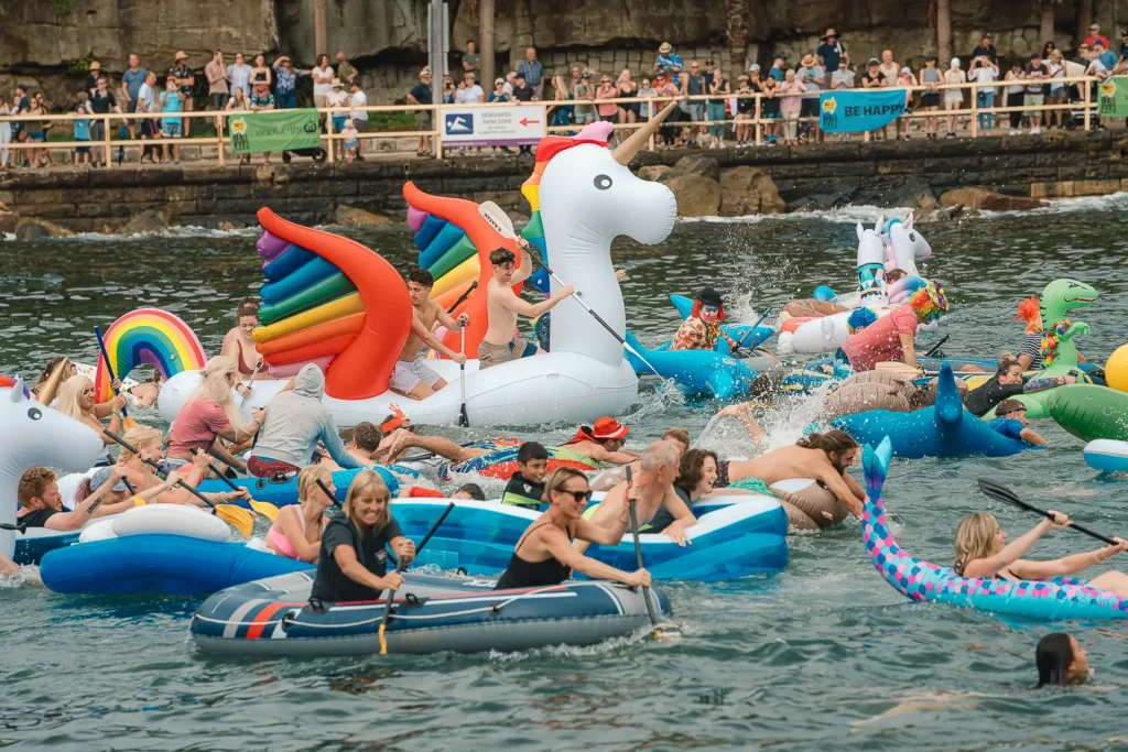 Giant rainbow unicorn surrounded by paddlers and colourful inflatables at Manly