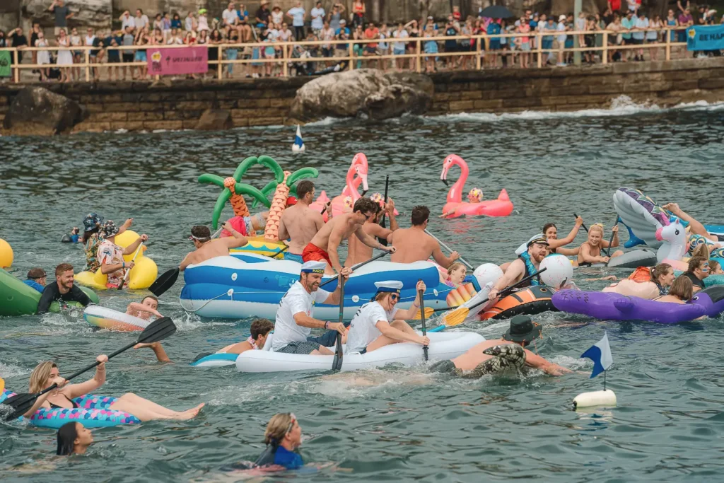 Groups of paddlers racing on inflatable boats and novelty floats at Manly