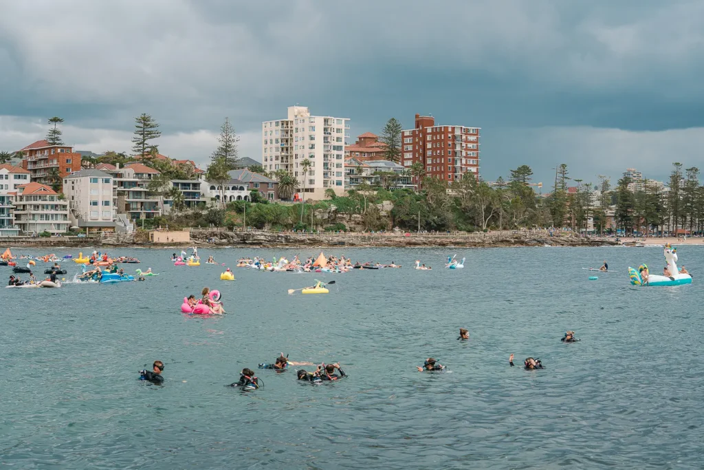 Wide view of inflatable racers and safety divers off Manly under a dramatic cloudy sky
