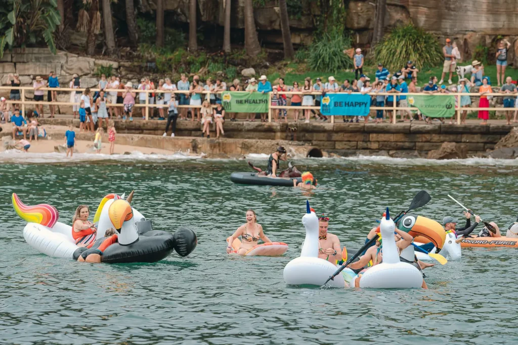 Participants riding toucan and unicorn inflatables during the Manly boat race