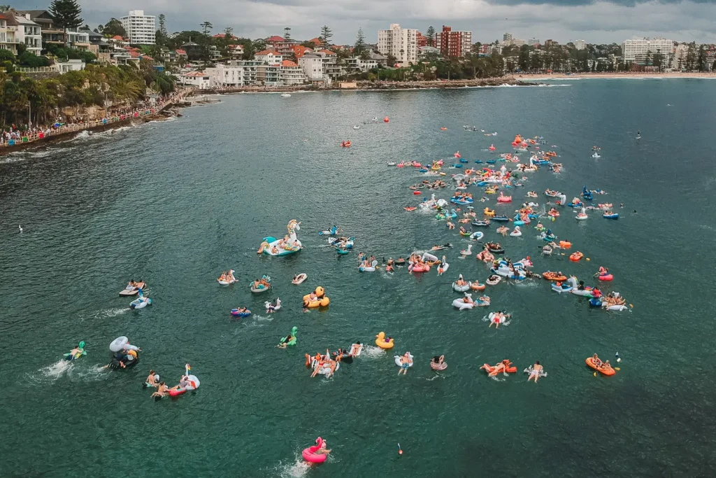 Aerial view of the Manly Inflatable Boat Race with participants spread across the water near Shelly Beach