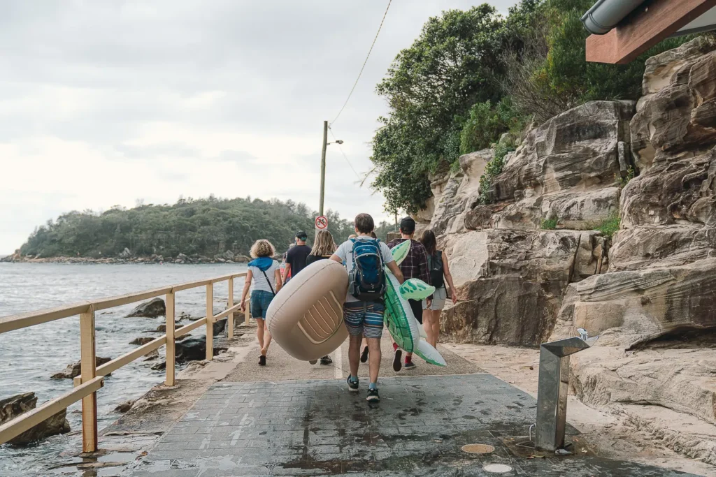 Participants carrying large inflatables along the coastal walk to Shelly Beach in Manly