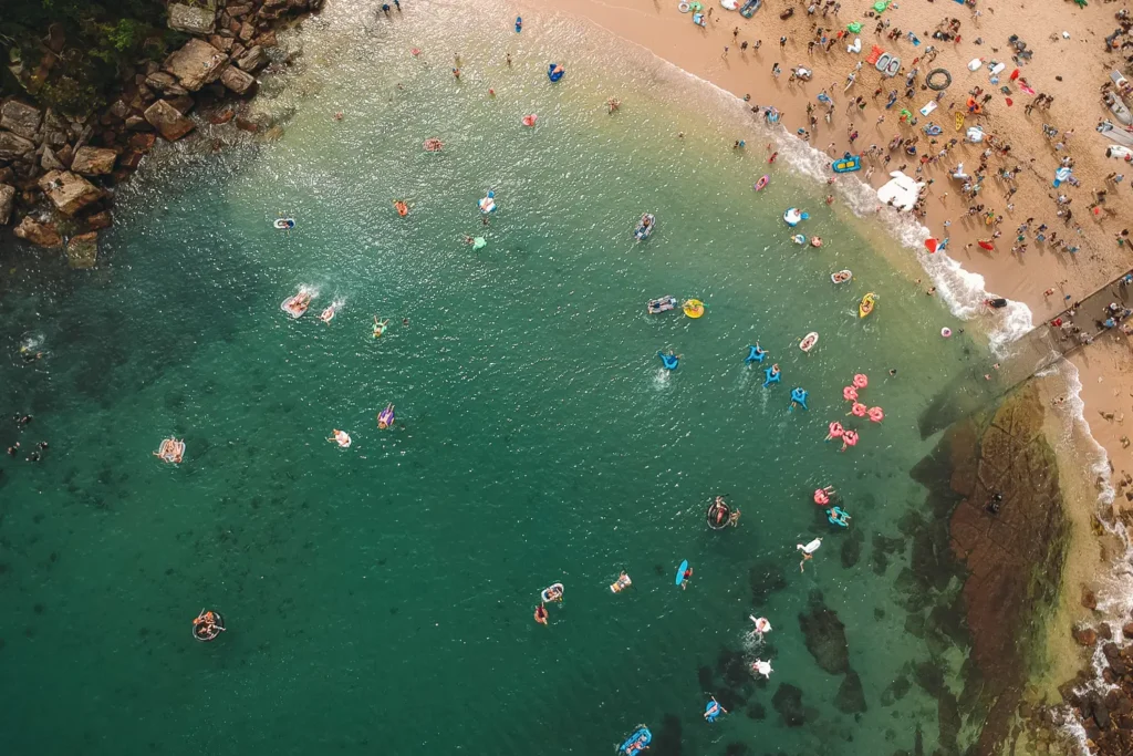 Top-down drone view of inflatable race participants along the shoreline at Shelly Beach