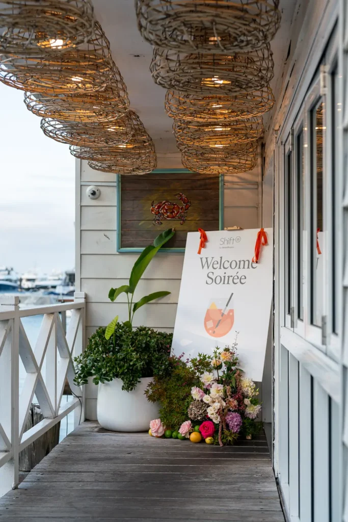 Shift Welcome Soirée entrance sign with flowers and coastal venue styling