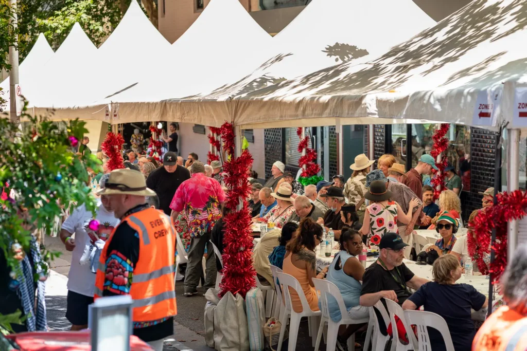 Busy Wayside Chapel Christmas lunch with guests gathered beneath festive marquees