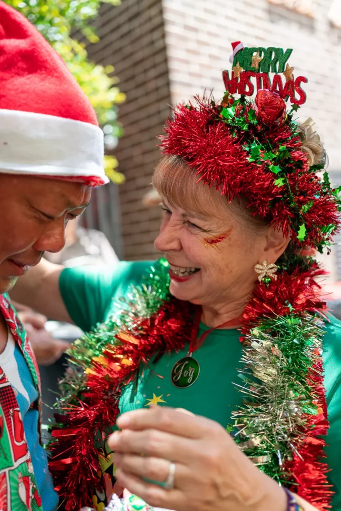 Smiling guests in colourful tinsel and Christmas hats at the Wayside Chapel celebration