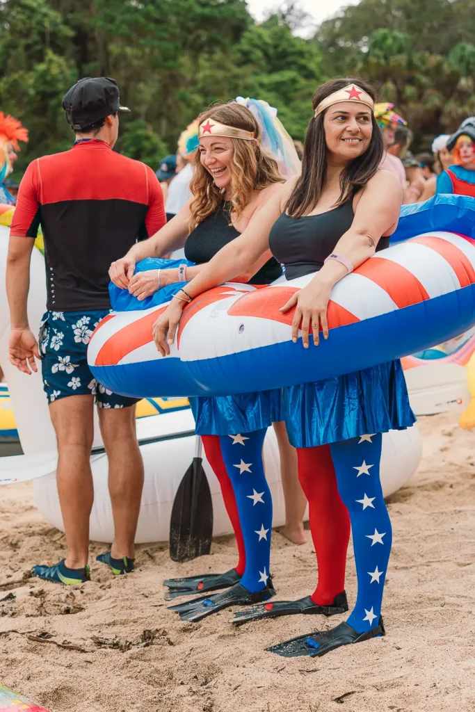 Two participants in Wonder Woman inspired costumes with an inflatable at Shelly Beach