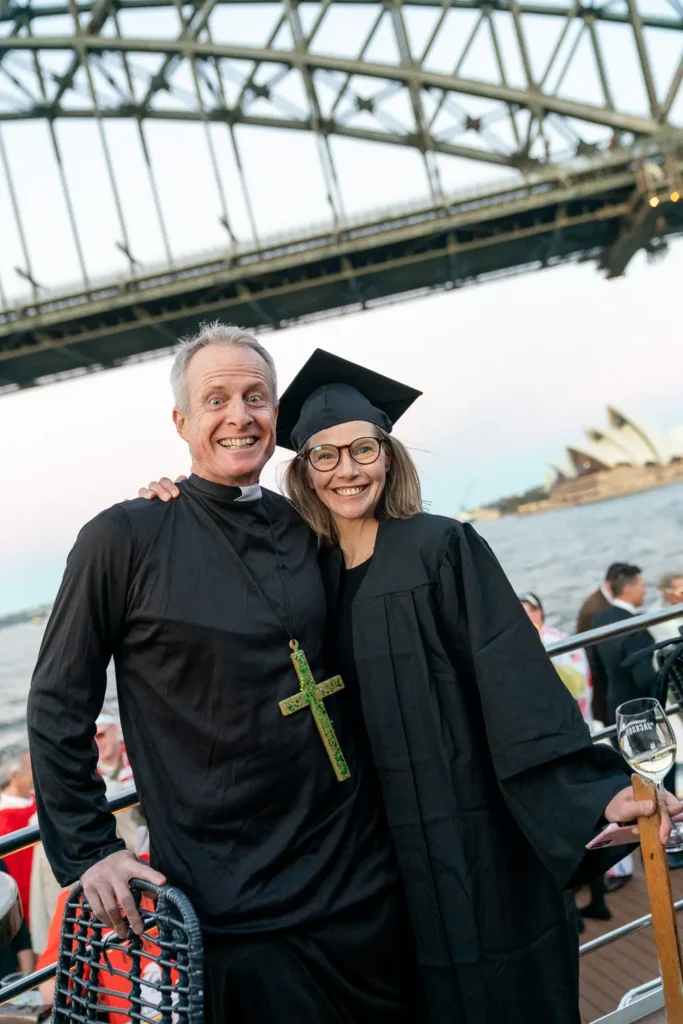 Guests dressed in priest and graduation costumes at a Sydney Harbour corporate event