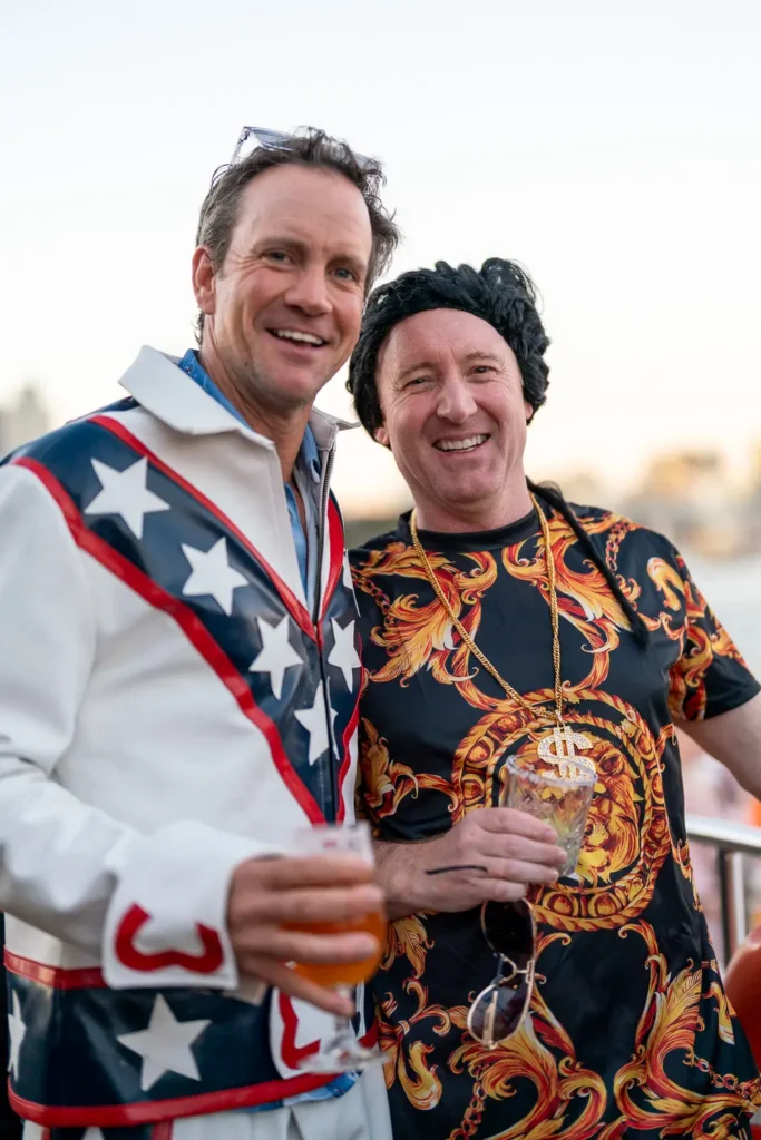 Two guests in colourful costumes enjoying drinks at a Sydney corporate party