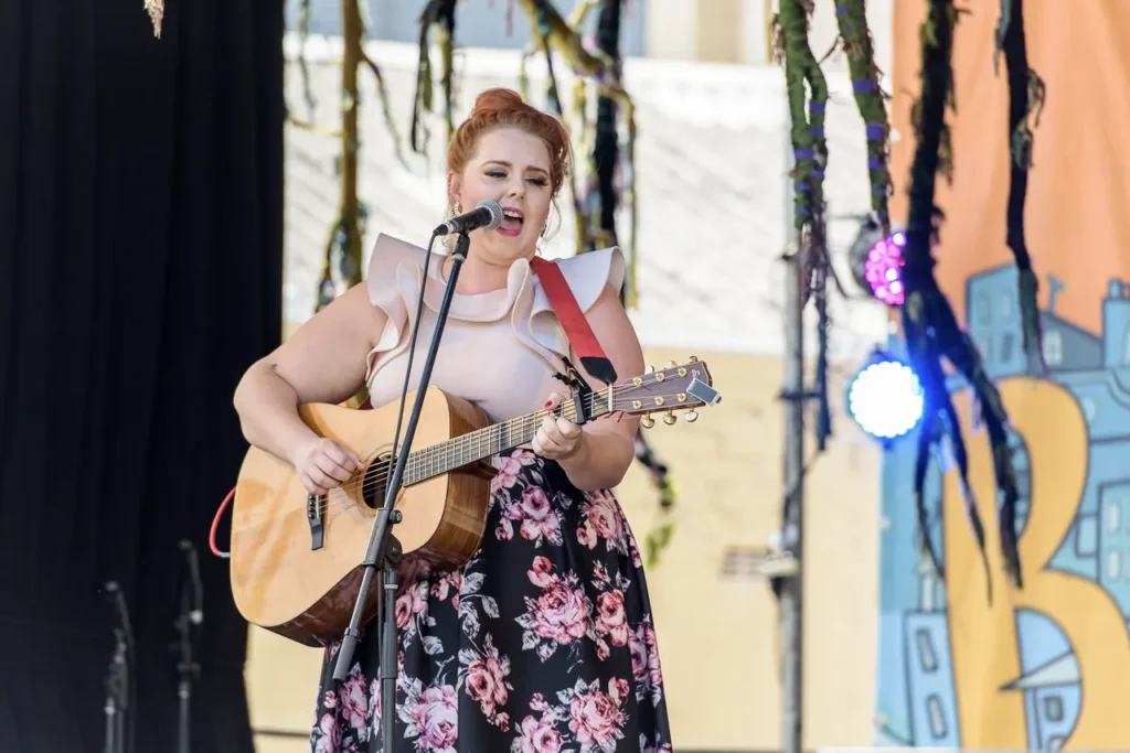 Close-up event photography of a female musician singing and playing acoustic guitar at Glebe Street Fair