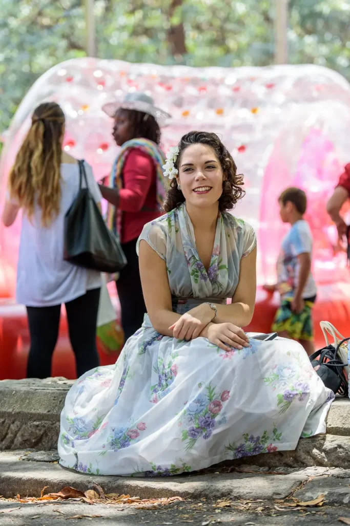 Candid festival portrait of a smiling woman in a floral dress enjoying the colourful atmosphere of Glebe Street Fair