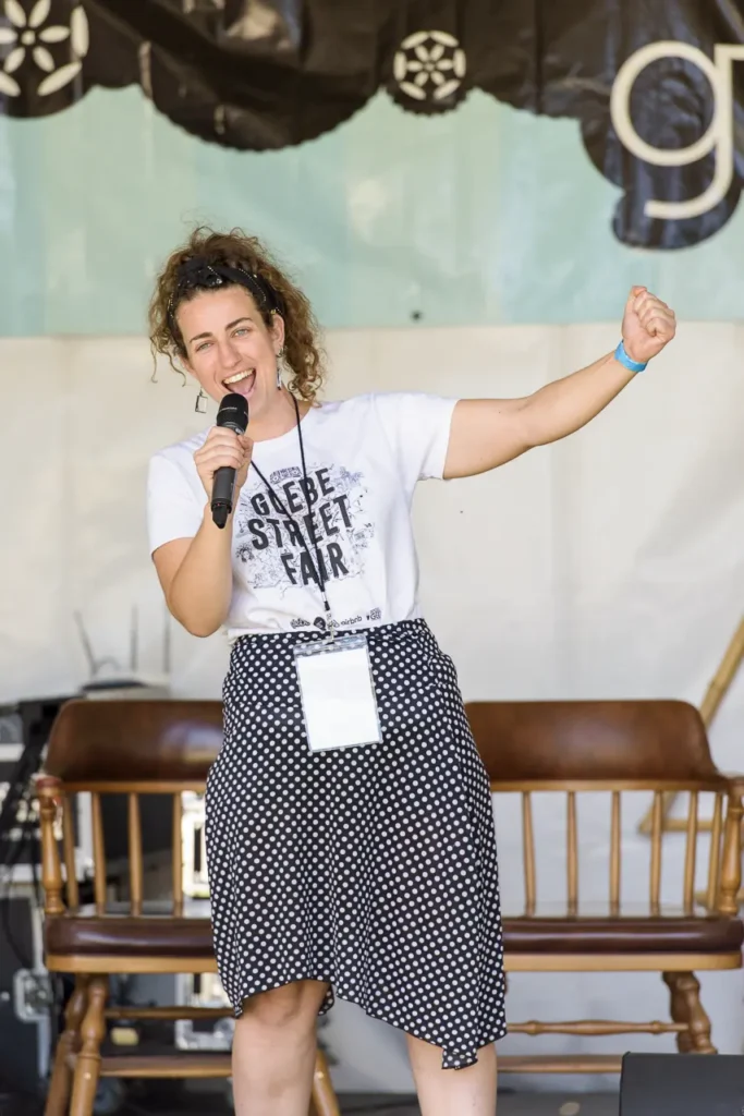 Energetic female MC speaking into a microphone on stage at Glebe Street Fair Sydney