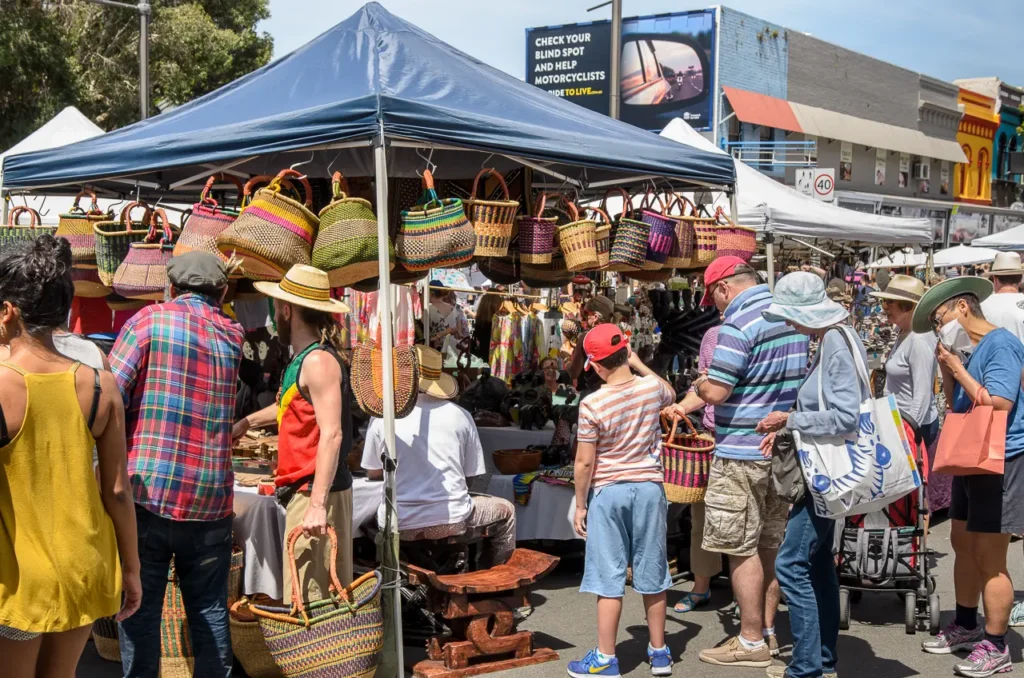 Busy outdoor market featuring colourful woven baskets, handmade crafts and shoppers at Glebe Street Fair Sydney