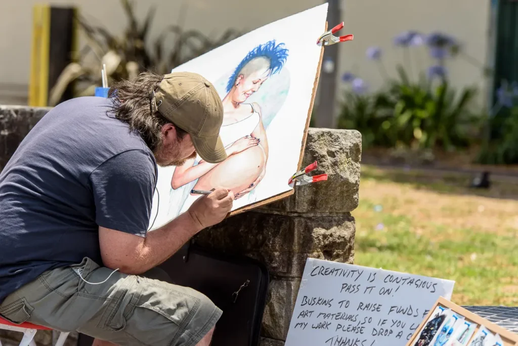 Street artist creating a colourful portrait outdoors at Glebe Street Fair Sydney
