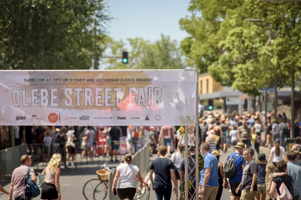 Glebe Street Fair entrance banner overlooking crowds along Glebe Point Road during the Sydney community festival
