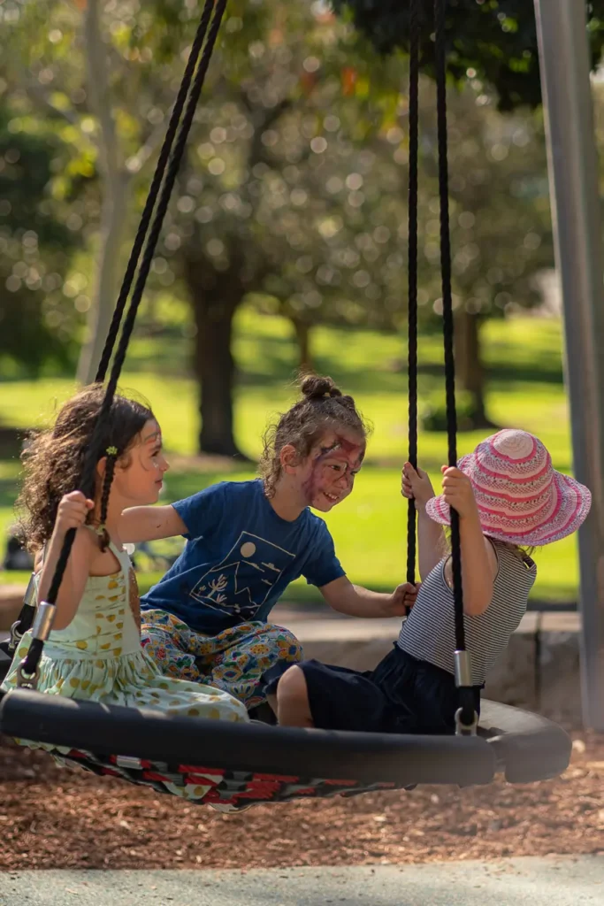 Event photography in North Sydney capturing children enjoying the swing at the St Leonards Park playground opening