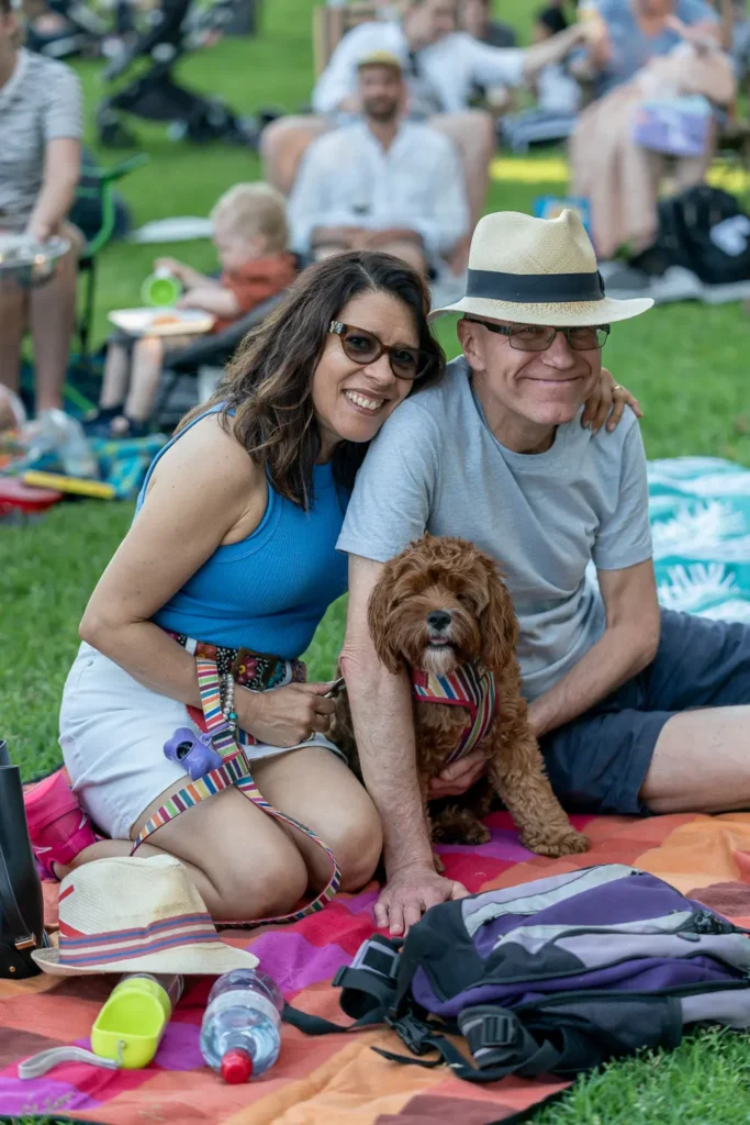 Smiling couple posing with their dog at the Sunset Series community event