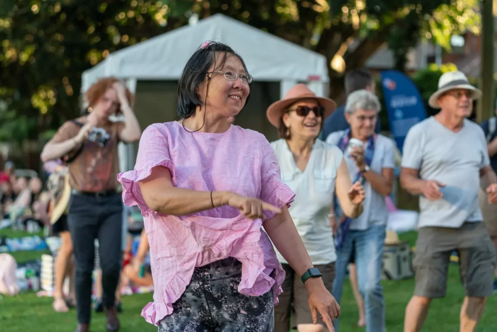 Festival guests dancing together on the grass during Sunset Series at Waverton Park
