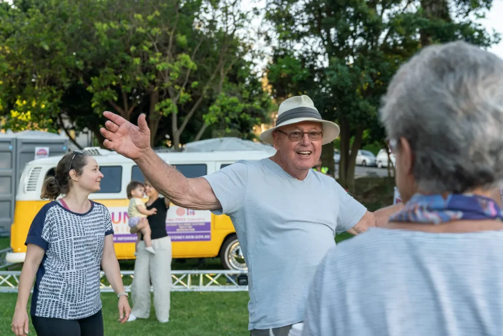 Older festival attendee dancing with arms outstretched at the Sunset Series community event