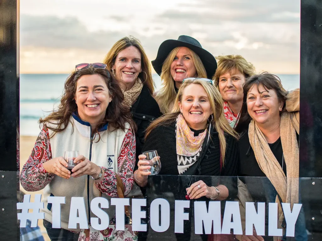 Group of friends posing by Manly Beach at the Taste of Manly festival