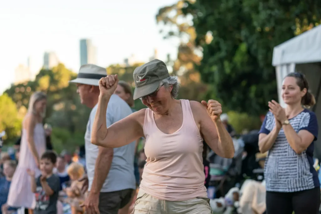 Woman dancing enthusiastically among festival attendees at North Sydney Sunset Series